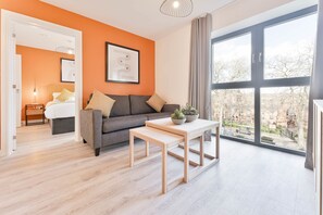 Ein modernes Wohnzimmer mit einer Couch, einem Couchtisch und einem großen Fenster mit Blick auf die Stadt.