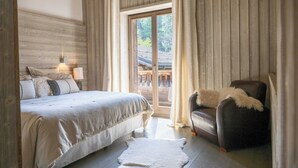 Ein Schlafzimmer mit Bett, Stuhl, Lampe und Blick durch ein Fenster.