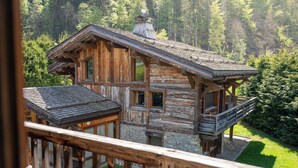 Eine rustikale Blockhütte mit Balkon, umgeben von üppigem Grün.