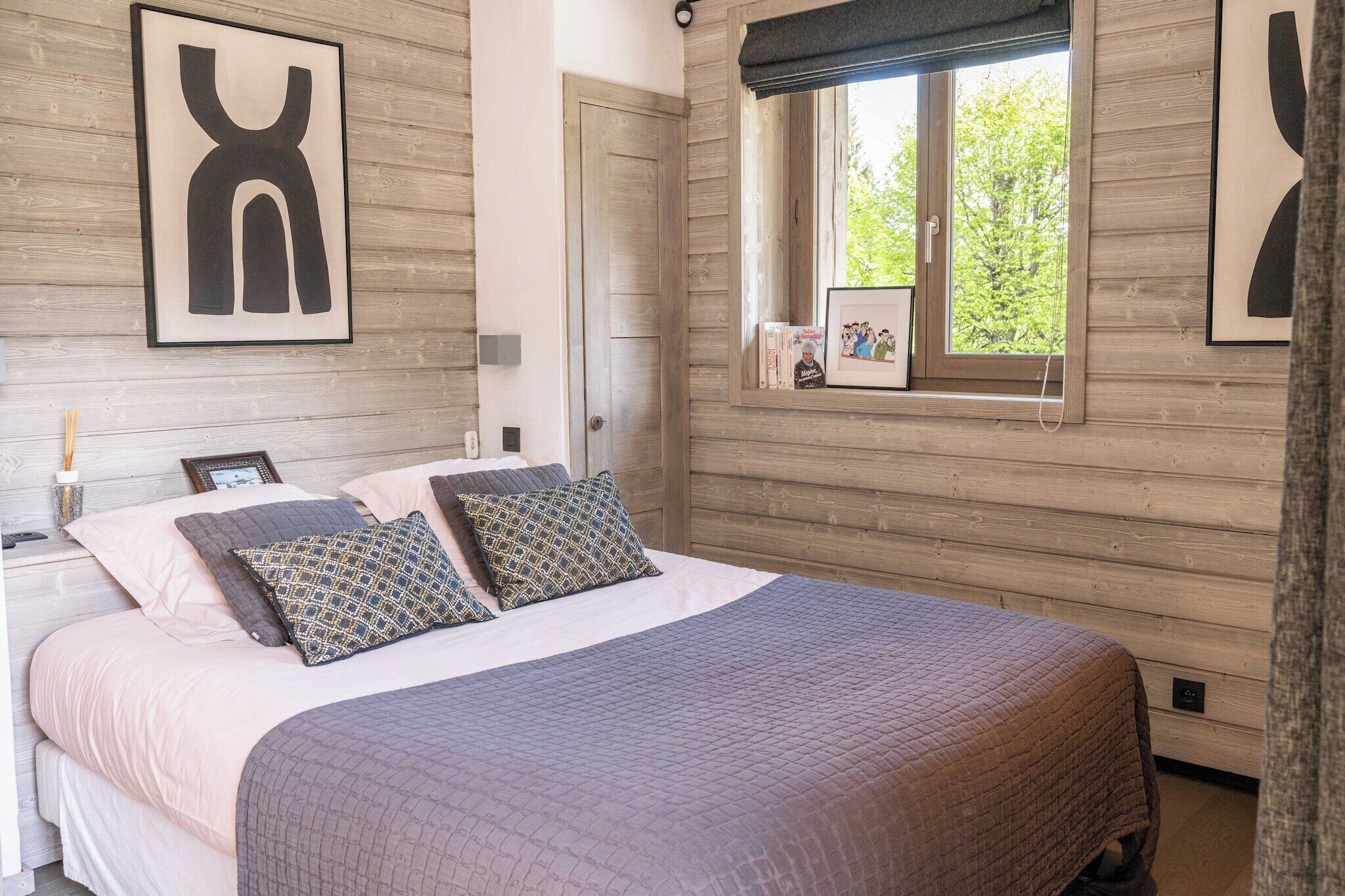 A bedroom with a large bed, a window with a view, and a framed picture on the wall.