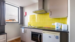 Uma cozinha compacta com janela, forno embutido, máquina de lavar louça e painel de cozinha amarelo.