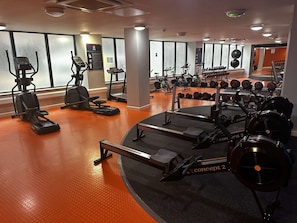 A gym with treadmills, elliptical machines, and a variety of weights.