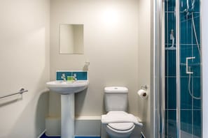 Une salle de bain avec un lavabo sur colonne, des toilettes et une douche à parois de verre.