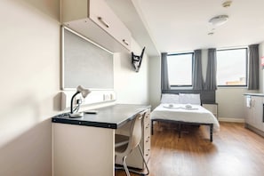 Une chambre d’hôtel moderne équipée d’un bureau, d’une chaise, d’un lit et de grandes fenêtres.