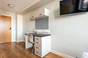 Une cuisine moderne équipée d’une cuisinière intégrée, d’un four à micro-ondes et d’un grand téléviseur à écran plat fixé au mur.
