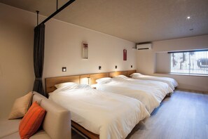 A hotel room with three beds, a sofa, a window, and a wall-mounted air conditioner. - 3minute walk from Hakodate Station  Accommodates / Hakodate City Hokkaidō (Hakodate City)