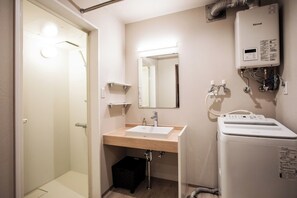 Une salle de bain équipée d’une douche, d’un lavabo, d’un miroir et d’un chauffe-eau Rinnai.