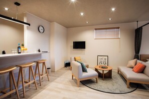 A modern living space with a kitchen area, bar stools, a sofa, a coffee table, and a TV mounted on the wall. - 3minute walk from Hakodate Station  Accommodates / Hakodate City Hokkaidō (Hakodate City)