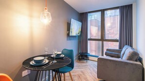 Ein modernes Zimmer mit Esstisch, Stühlen, einer Couch und einem großen Fenster mit Vorhängen.