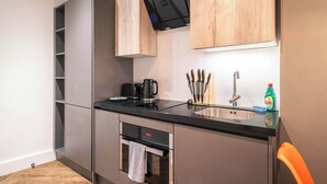 Eine kleine Küche mit schwarzem Arbeitsplatz, Spüle aus Edelstahl und modernen Geräten.