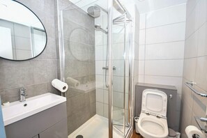 Ein modernes Badezimmer mit Duschkabine aus Glas, Waschbecken und Toilette.