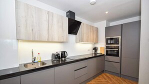 Una cocina moderna con armarios grises, encimera negra y suelo de madera.