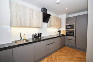 Eine moderne Küche mit grauen Schränken, einer schwarzen Arbeitsplatte und einem Holzboden.