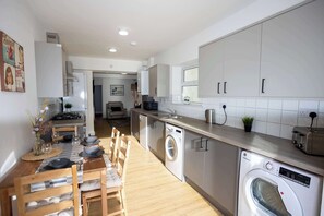 Eine moderne Küche mit Essbereich, eingebauten Geräten und Blick zum Wohnzimmer.