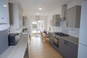 Eine moderne Küche mit Essbereich, Holzboden und einem großen Fenster.