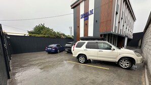 A parking area with two cars, a building labeled 'DREAM HOTEL,' and a brick pavement. - Dream Hotel Mayram (Kok-Jar)