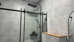 Une cabine de douche moderne dotĂ©e dâun pommeau de douche Ă pluie, dâun pommeau de douche Ă main et dâun distributeur de savon.