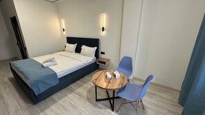 Une chambre dâhĂŽtel comprenant un lit, une table de chevet, deux chaises et une table ronde en bois.