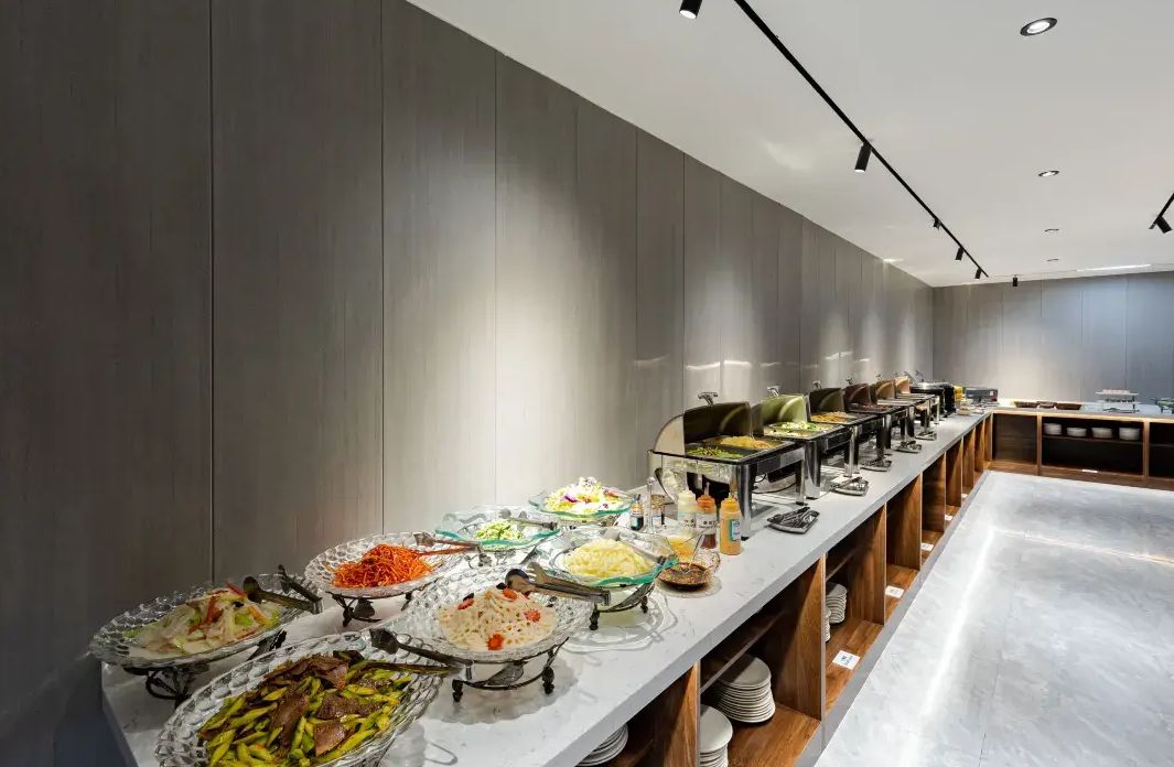 Disposição de buffet com diversos tipos de comida e um balcão extenso.