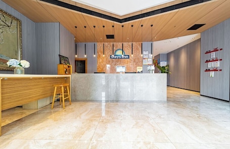 A reception area with a marble counter, wooden accents, and a sign for Days Inn.. Days Inn Xi'an City Center