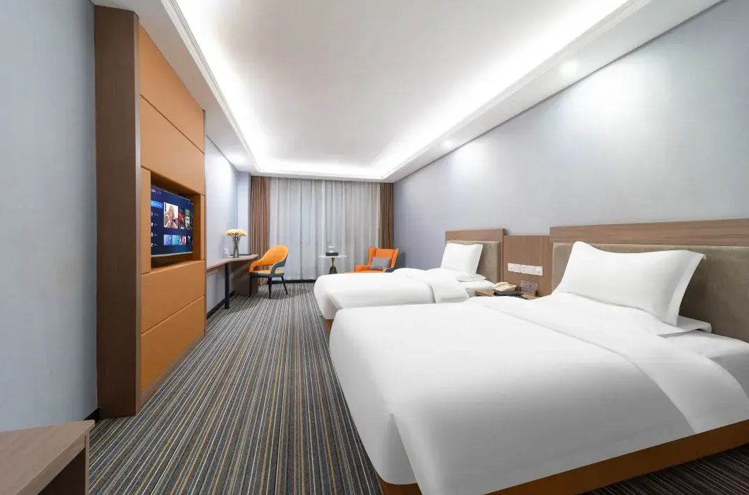 Habitación de hotel con dos camas, un escritorio y una zona de estar.