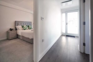 Ein Schlafzimmer mit Bett, Nachttisch und einem kleinen Tisch. Eine Tür führt zu einem Balkon.