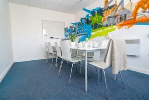 A conference room with a whiteboard, a table with chairs, and a colorful abstract painting on the wall. - Coventry Budget Studio w/ Gym & Games Room (Coventry)