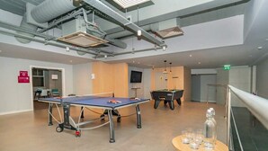 Een kamer met een tafeltennistafel, een pooltafel en een kleine tafel met glazen.