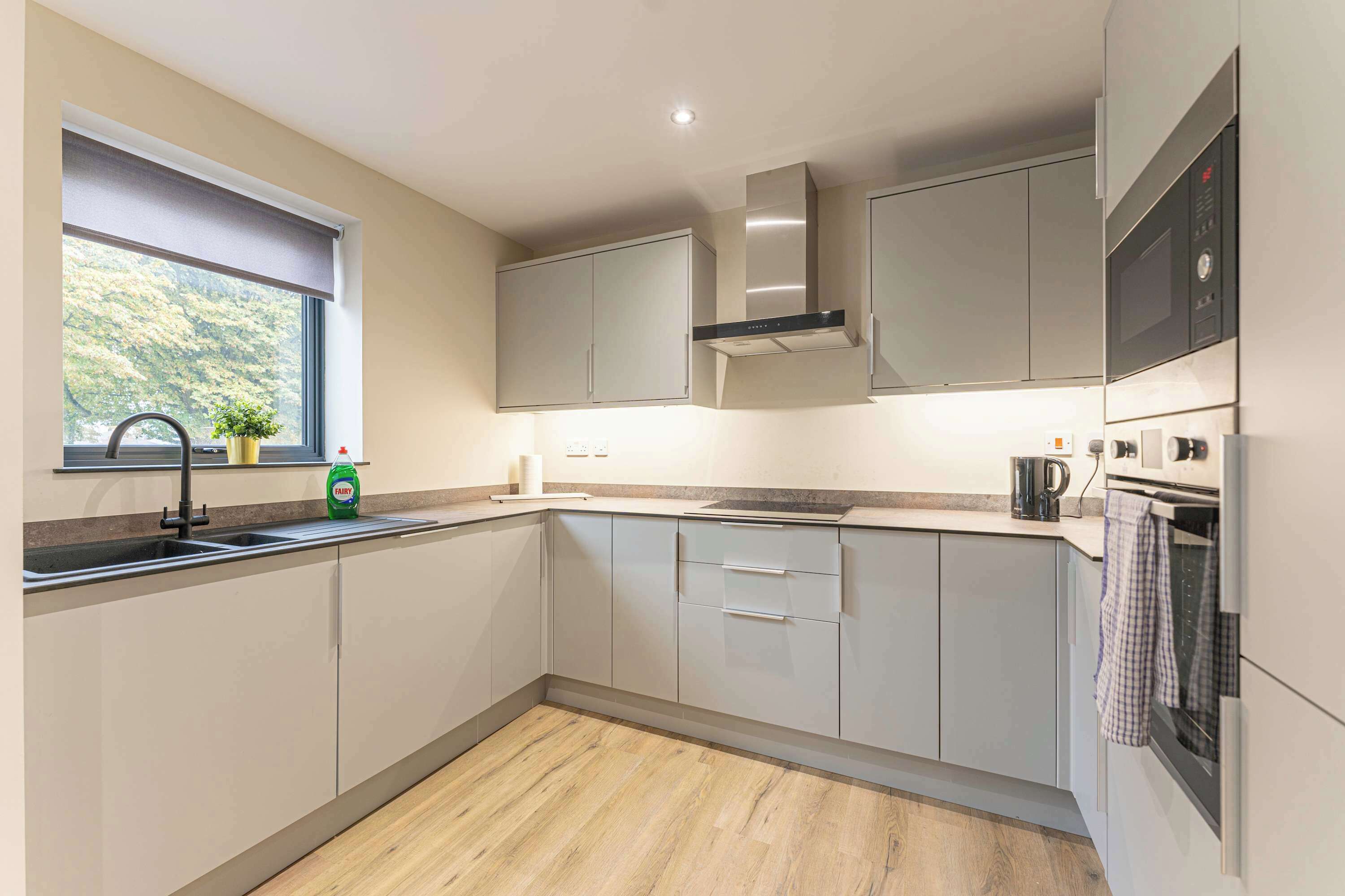 A modern kitchen with a window, stainless steel appliances, and light-colored cabinetry.