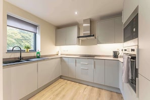 Eine moderne Küche mit Fenster, Edelstahlgeräten und hellen Küchenschränken.