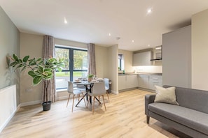 Un apartamento moderno con comedor, cocina y un sofá gris.