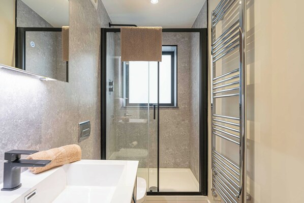 Une salle de bain moderne avec une douche à parois de verre, un lavabo blanc et un porte-serviettes.