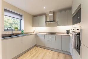 Una cocina moderna con ventana, electrodomésticos de acero inoxidable y suelo de madera.