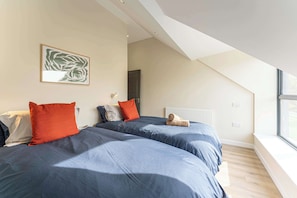 Ein Schlafzimmer mit zwei Betten, einem Heizkörper, einem Fenster und einer Decke mit einem Dachfenster.