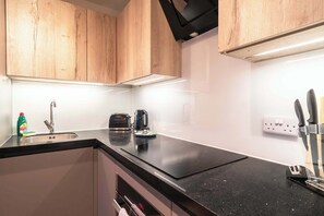 Eine Küche mit Holzschränken, einer schwarzen Arbeitsplatte, einem Wasserkocher, einem Toaster und einem Spülbecken.