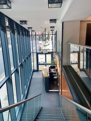 A modern interior with a staircase, a reception desk, and large windows offering views of the street. - Modern Studio Apartment in Central Hastings (East Sussex)
