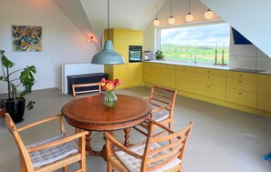 Ein Essbereich mit einem runden Holztisch, vier Korbstühlen und einer Blumenvase.