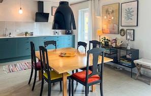 Eine moderne Küche mit türkisfarbenen Schränken, einem Holztisch und bunten Stühlen.