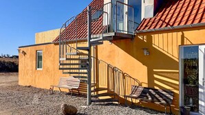 Ein gelbes Gebäude mit rotem Ziegeldach, einer Treppe und einer Bank.