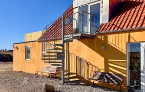A yellow building with a red-tiled roof, a staircase, and a bench. - Gorgeous apartment in Ebeltoft with WiFi (Ebeltoft)