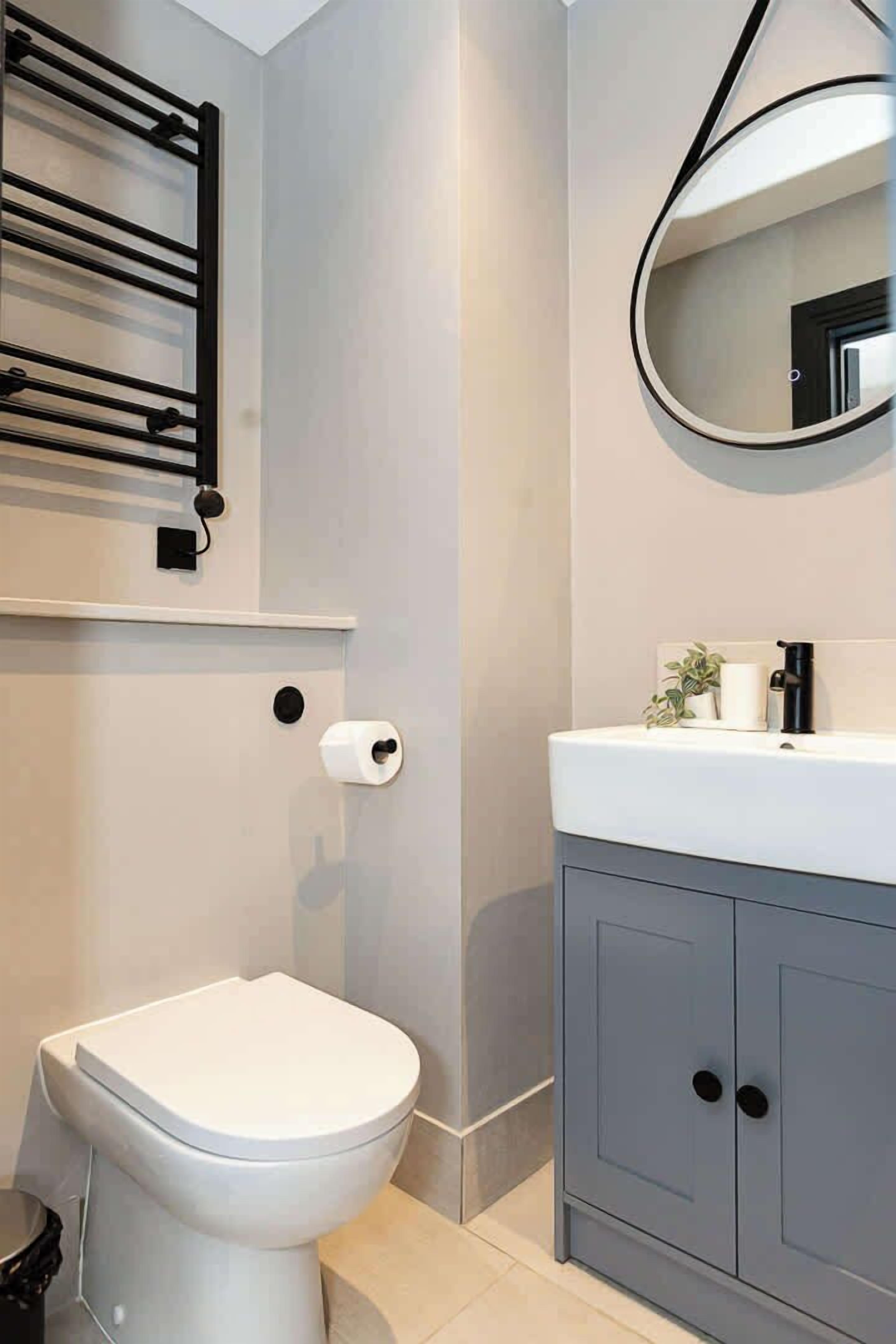 Ein Badezimmer mit Toilette, Handtuchhalter, Spiegel und Waschbecken mit Schränken.