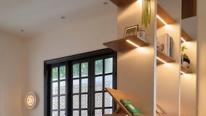 A modern interior with a dining area, bookshelves, and a window with decorative glass panels. - Hanachi Stay Thao Dien (Ho Chi Minh City)