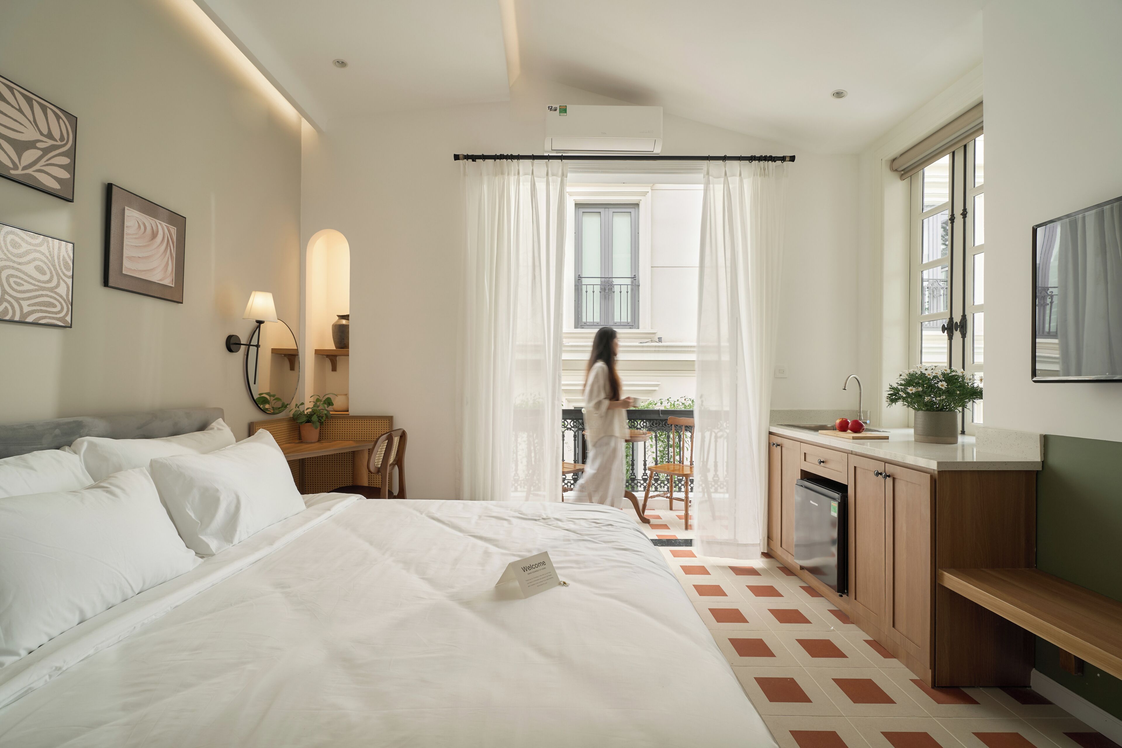 Une chambre d’hôtel avec un lit, un bureau, une petite kitchenette et un balcon avec vue.