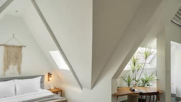 Quarto moderno no estilo loft, com teto inclinado, cama, área de estar e espaço de trabalho com escrivaninha e cadeira.