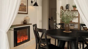 A dining area with a fireplace, white curtains, and a table with chairs. - Hanachi Stay Thao Dien (Ho Chi Minh City)