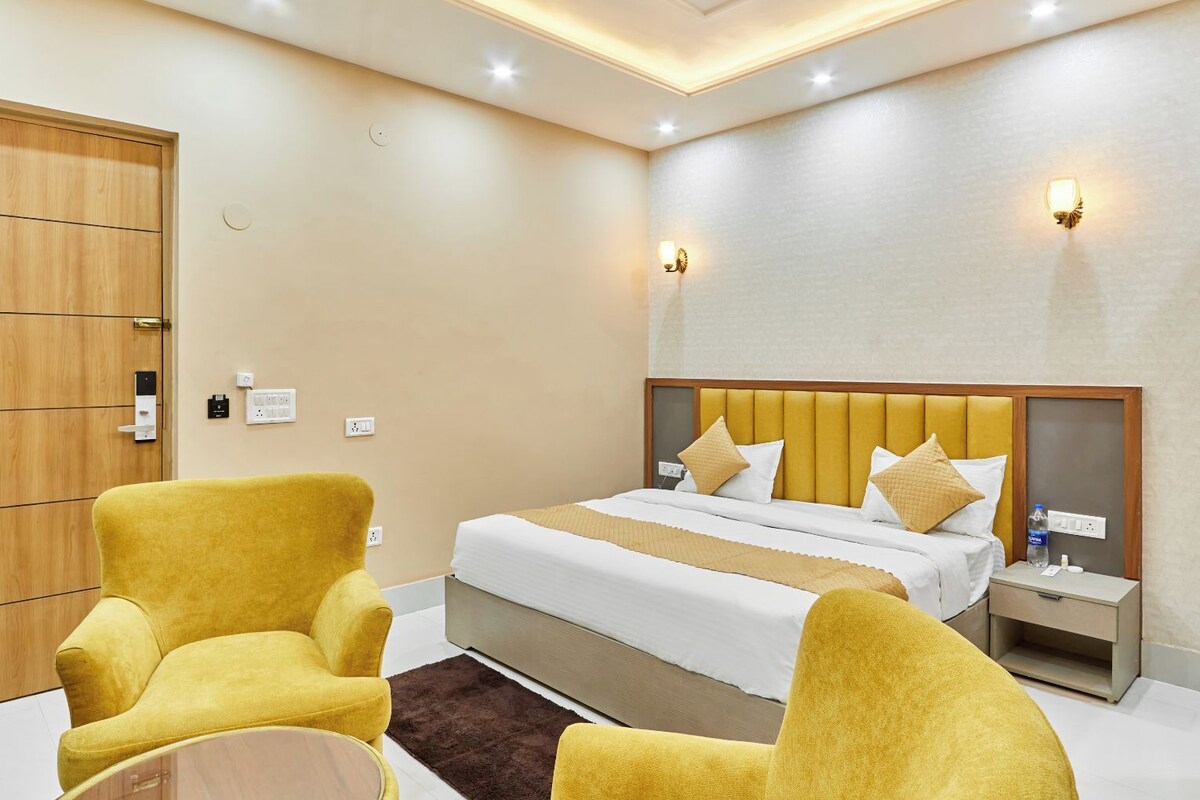 A hotel room with a bed, two armchairs, a nightstand, and a wooden wardrobe.