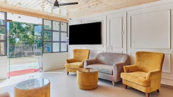 Un salon moderne avec un téléviseur à écran plat, deux fauteuils, un canapé et une table basse en verre.