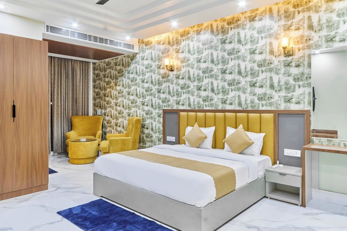 A hotel room with a bed, two chairs, a desk, and a wardrobe.