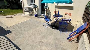 A patio area with a table and chairs, a blue umbrella, and potted plants.