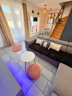 Un salon moderne avec un canapé, une table ronde et un escalier.